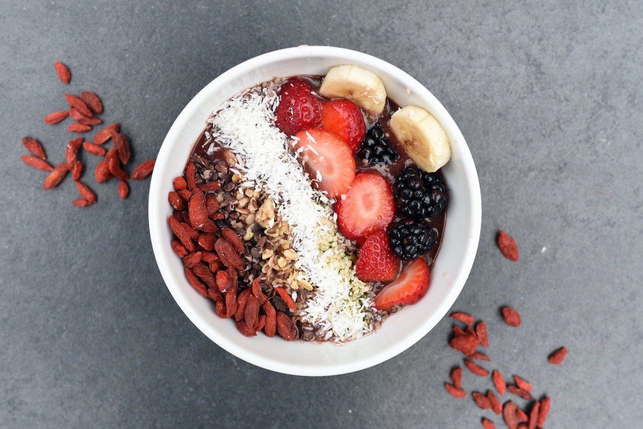 Bienfaits des super aliments - bol avec fruits frais, secs et aliments en poudre