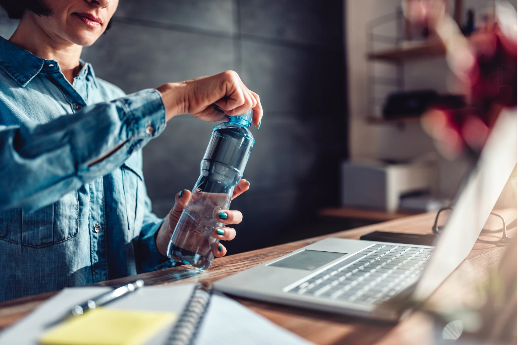 BulkBar - Fontaines à eau - 1 fontaines a eau au bureau - Femme en entreprise prête à ouvrir une bouteille d’eau devant son ordinateur