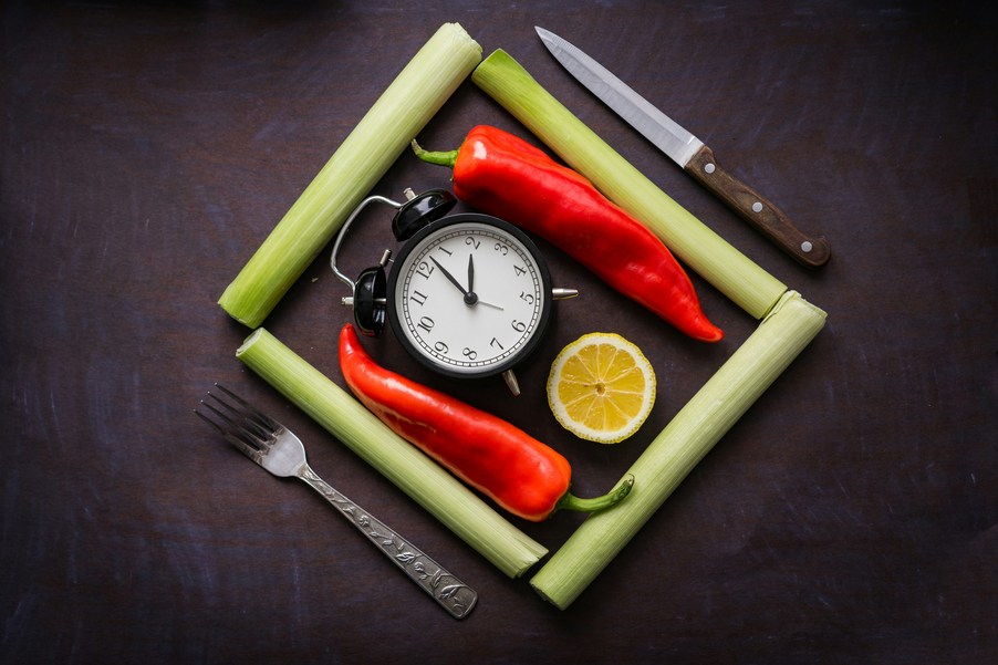 Jeune intermittent au travail - réveil entouré de légumes, citron et couverts